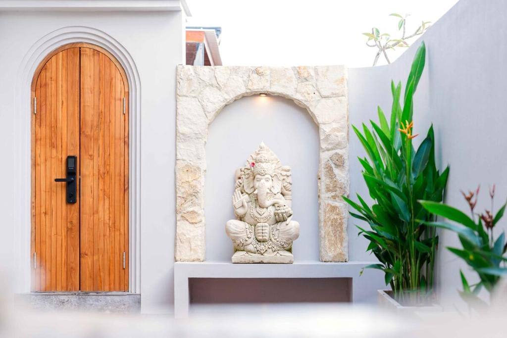 Eingang der Villa mit handgeschnitzter Holztür und Ganesha-Schrein